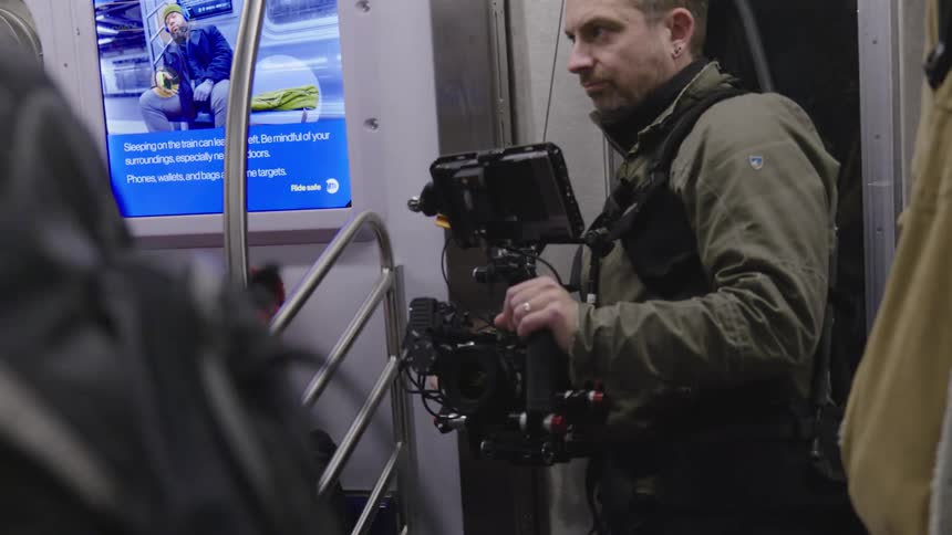 Camera operator takes video while standing near the entrance in a subway car