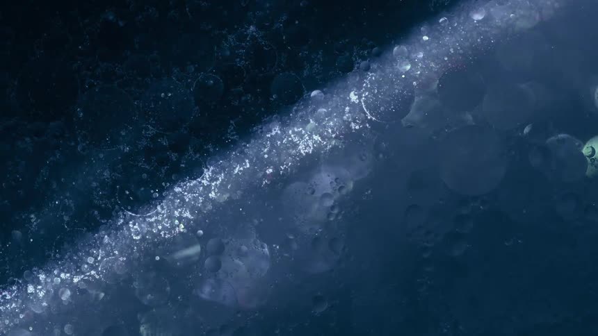 A dark blue abstract image features a diagonal band of light with scattered white specks