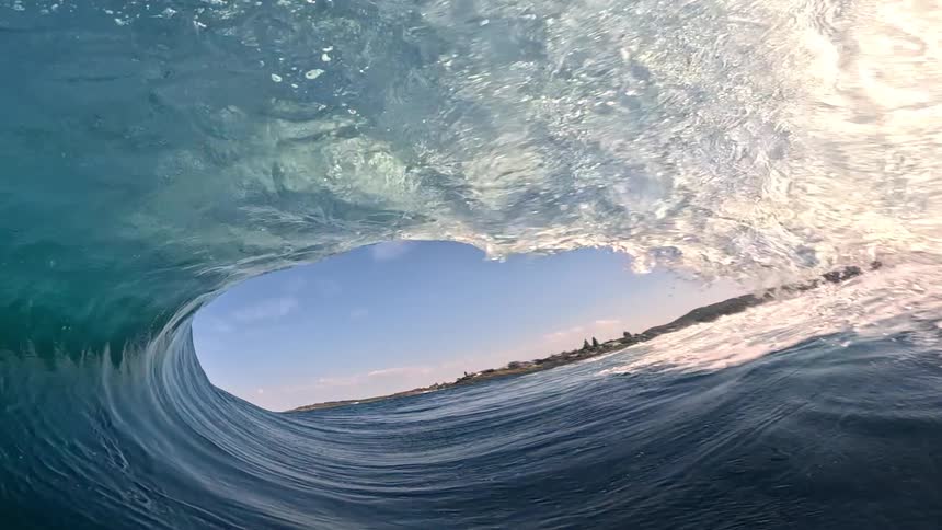 A surfer travels through the tunnel formed by a wave