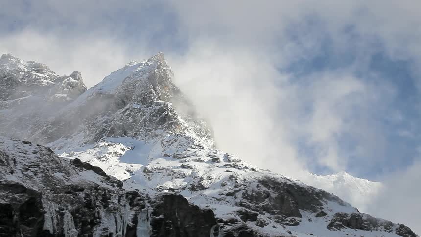 Clouds floating above snow covered mountains