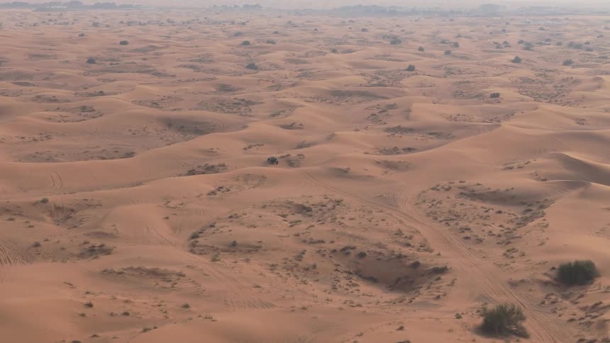 Aerial view of a black vehicle traveling at high speed through the desert