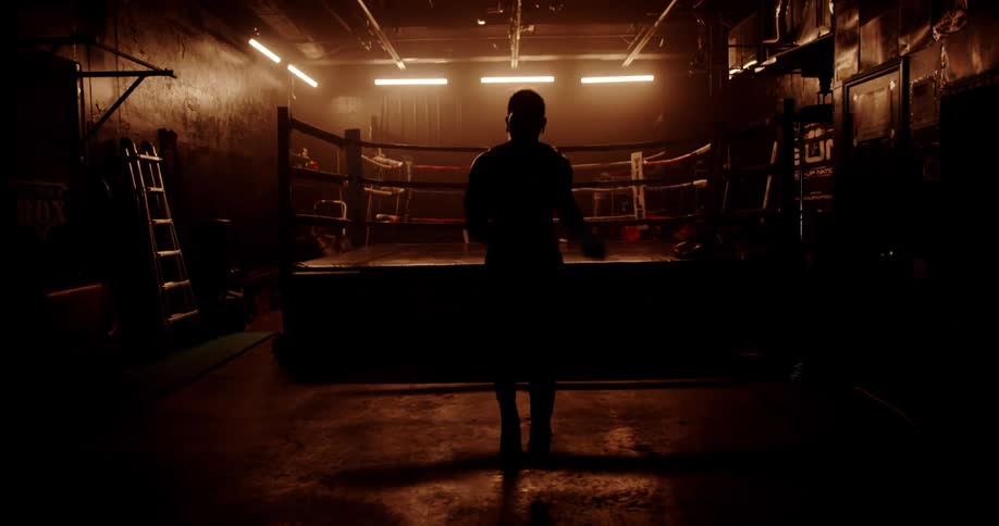 A man is jumping rope in a gym with a boxing ring