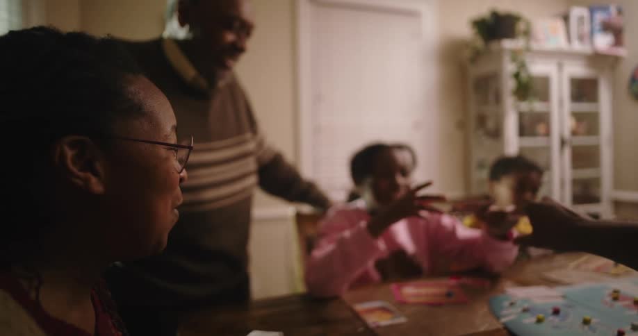 A family laugh and talk while playing a board game