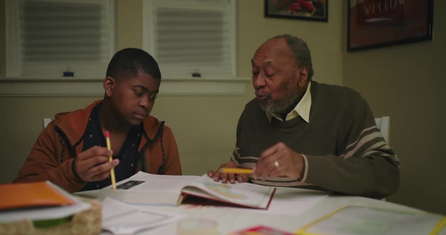 A grandfather is helping his grandson study