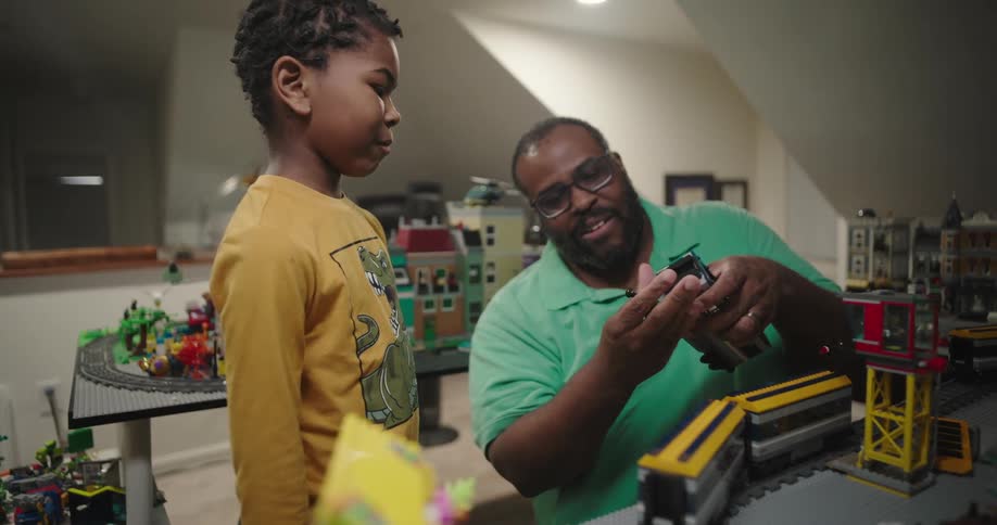 A father and son playing with a lego train set