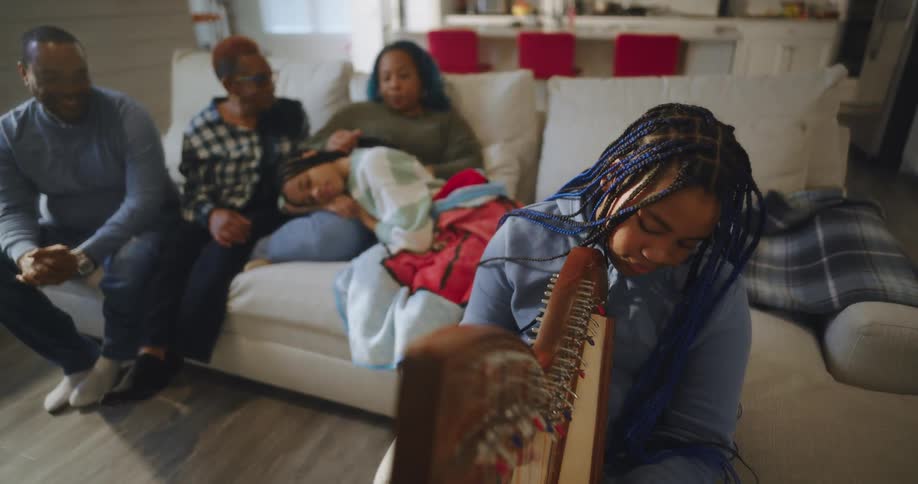 A family listen to a child play the harp