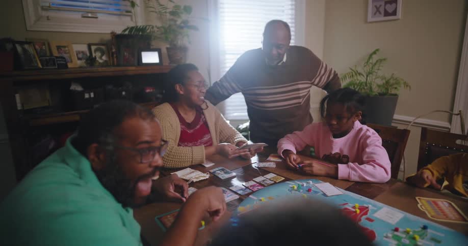 Family gathered around a table playing cards and board games
