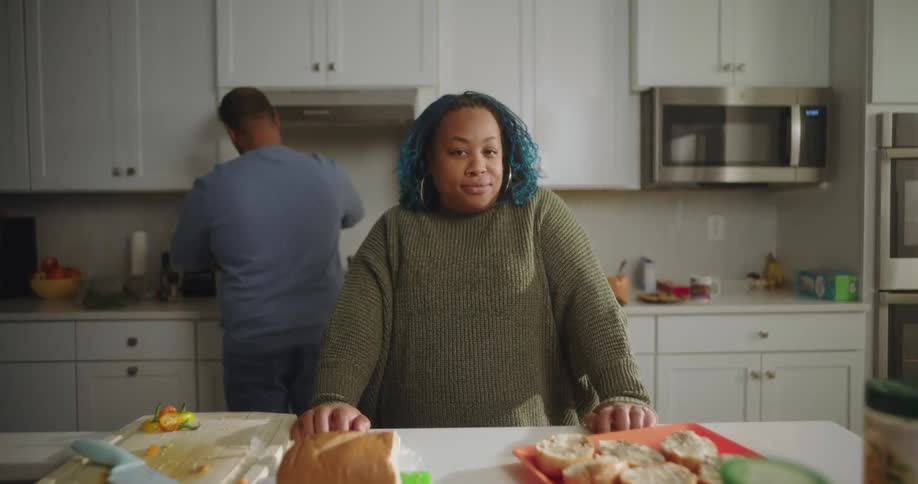A woman is leaning on the counter in her kitchen