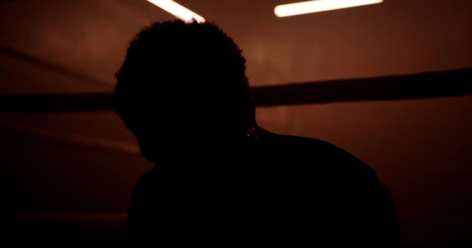 A man is breathing heavy and leaning against a boxing ring