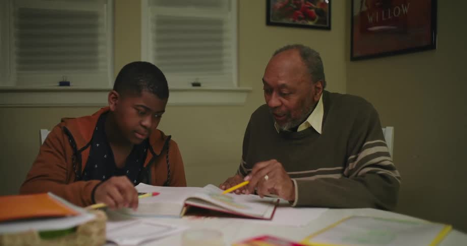 An adult helps a teenager with homework
