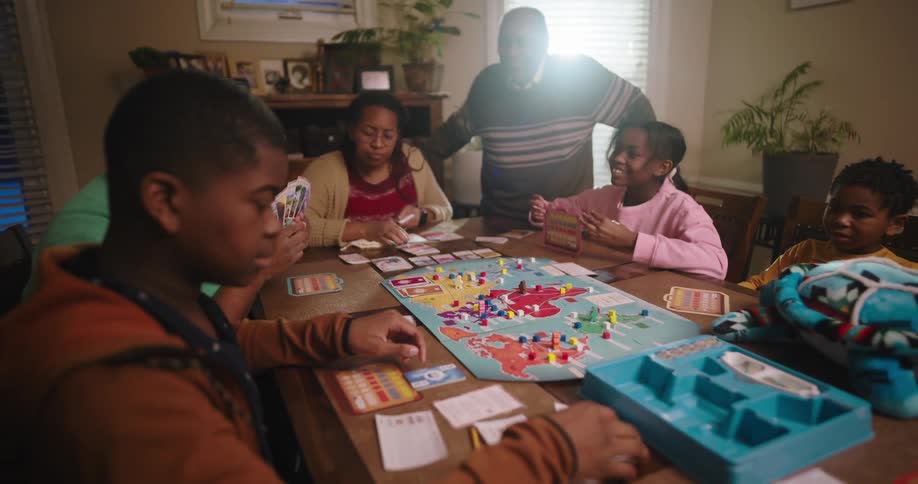 Family gathered around a table playing the board game war