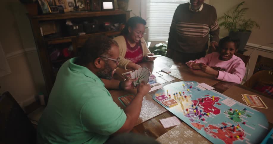 Father laughing enthusiastically while a playing board game with family
