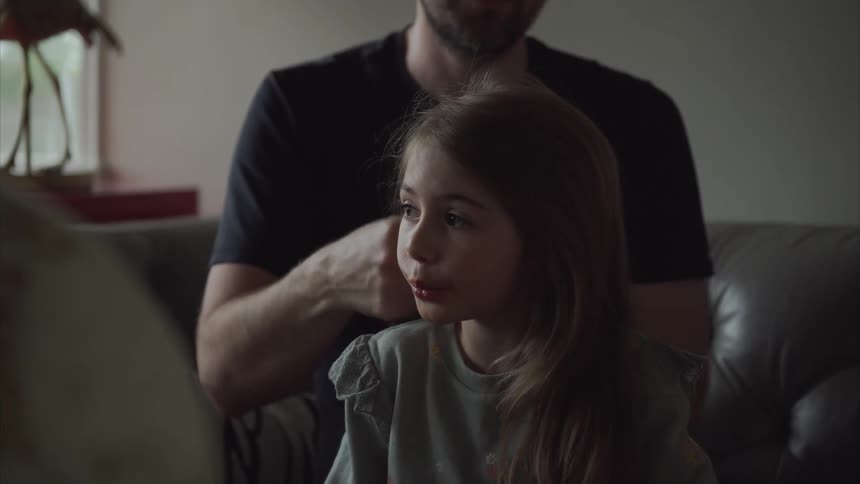 Father combing his daughters hair