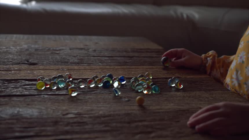 A little girl in a living room is playing with marbles on a table