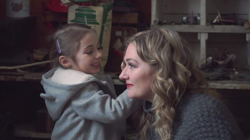A young girl explores a shell and then playfully interacts with a woman