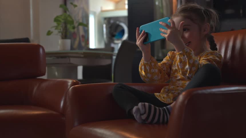 Little girl excitedly playing video game on a cell phone at home