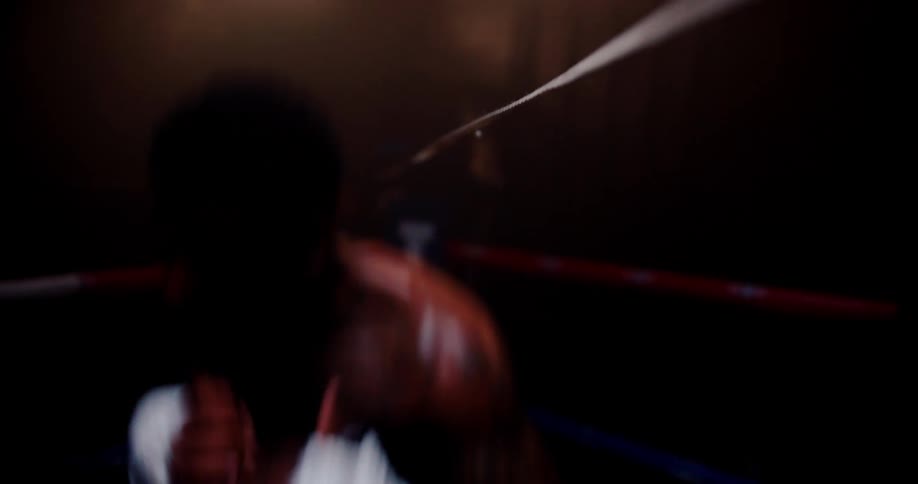 Man is boxing aggressively inside the ring at night time