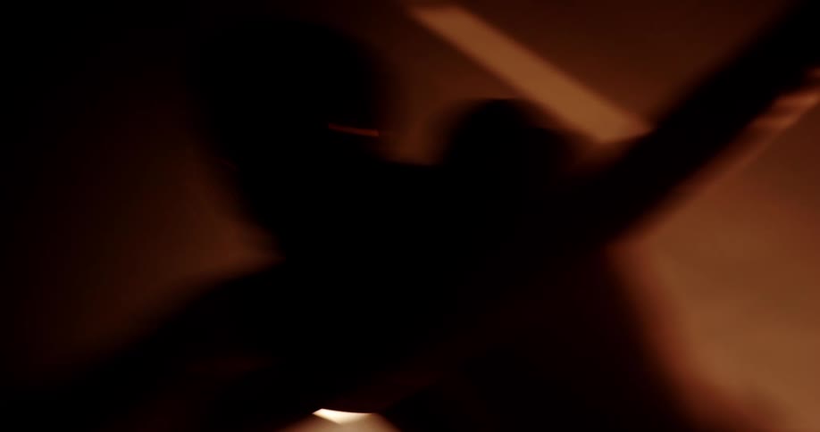 Silhouette of a boxer reclined on the ropes in a dimly lit gym