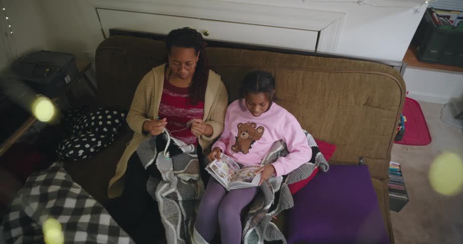Mother crochets while her daughter looks at a book
