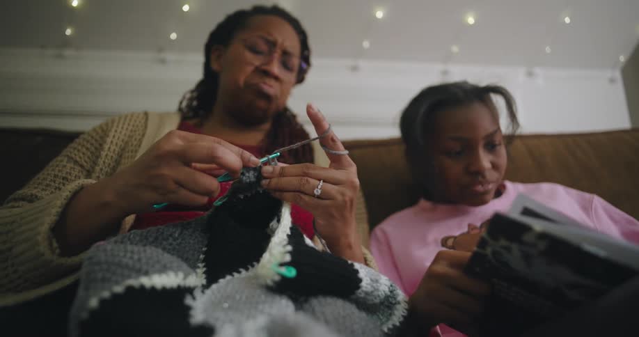Mother crochets whiles she listens to her daughter read a book