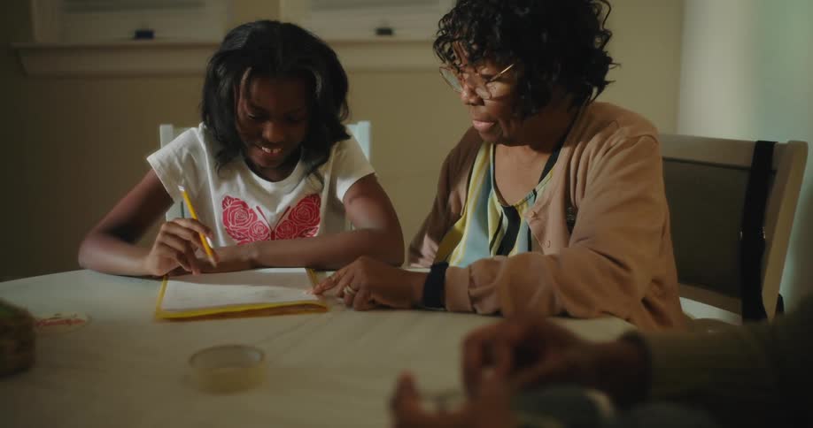 A mother helps her daughter with homework at home
