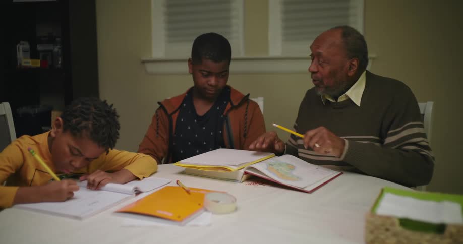A man helping two boys with homework