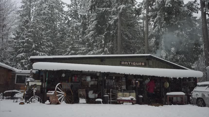 A man holding a baby walks toward a business in the snow