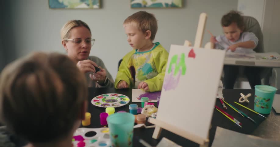A mother is helping her child paint with water colors