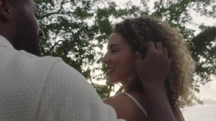 Man running his hands through his wifes curly hair in a happy and romantic moment outdoors