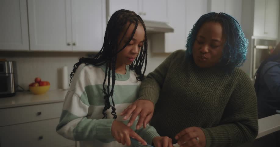 Parents cook with their daughters in their home kitchen on a sunny autumn day