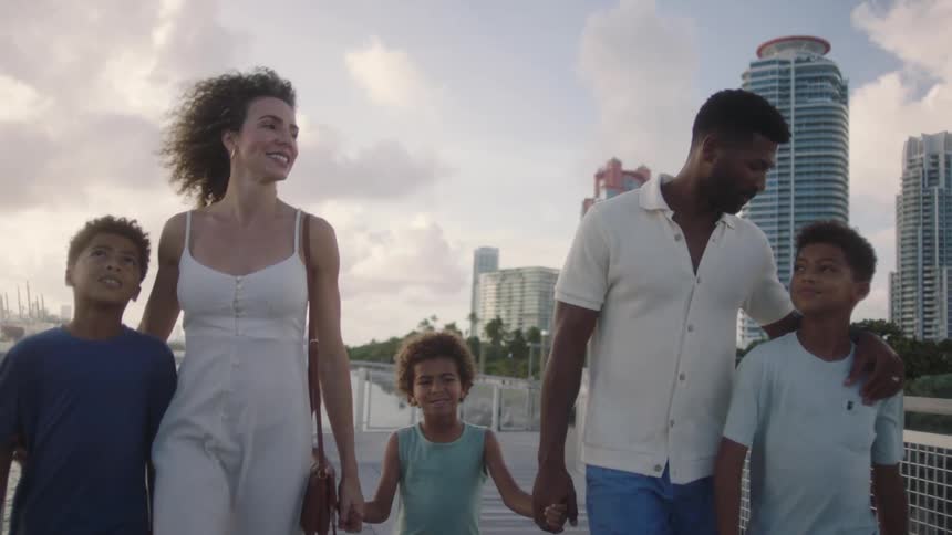 Family of five walking outdoors through a city holding hands
