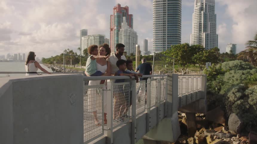 Family on a bridge enjoying the sea view with a metropolis in the background
