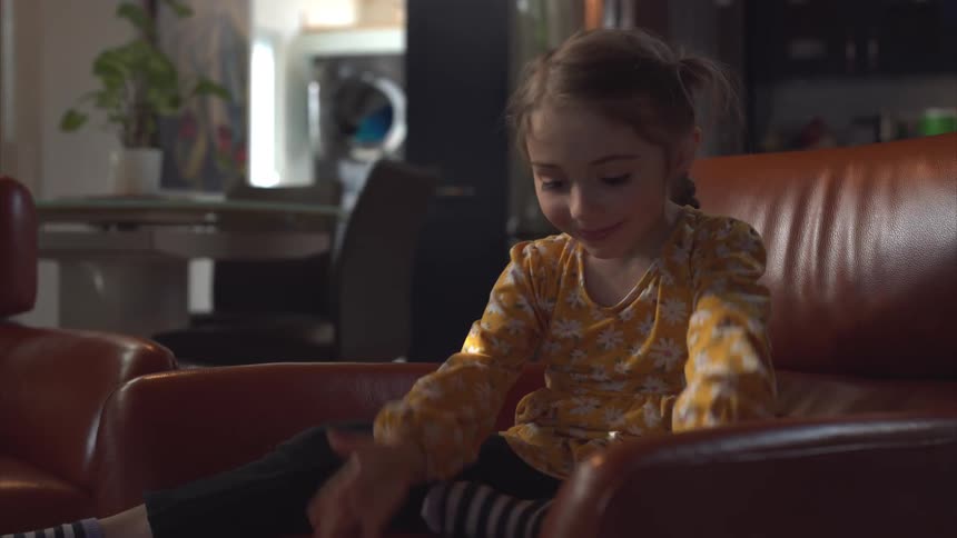 Little girl sitting in an armchair holding and interacting with a smartphone