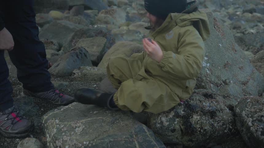 A child is picking up rocks on the shore