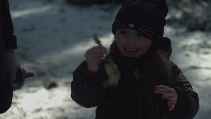 A child smiles and waves a twig around