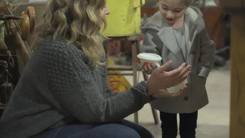 A mother and daughter examine decorative vases together in an antique shop