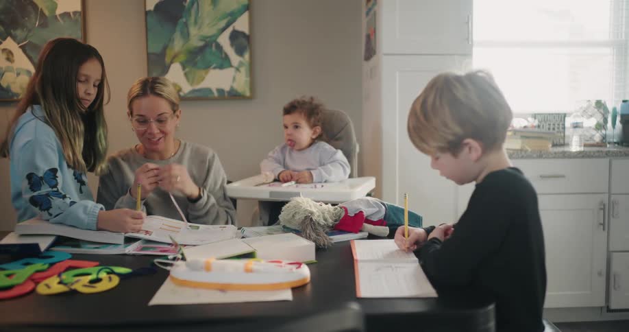 A mother helping her children with homework in the dining table at home