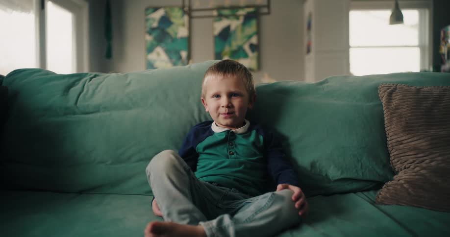 Young boy sitting on the living room couch smiles