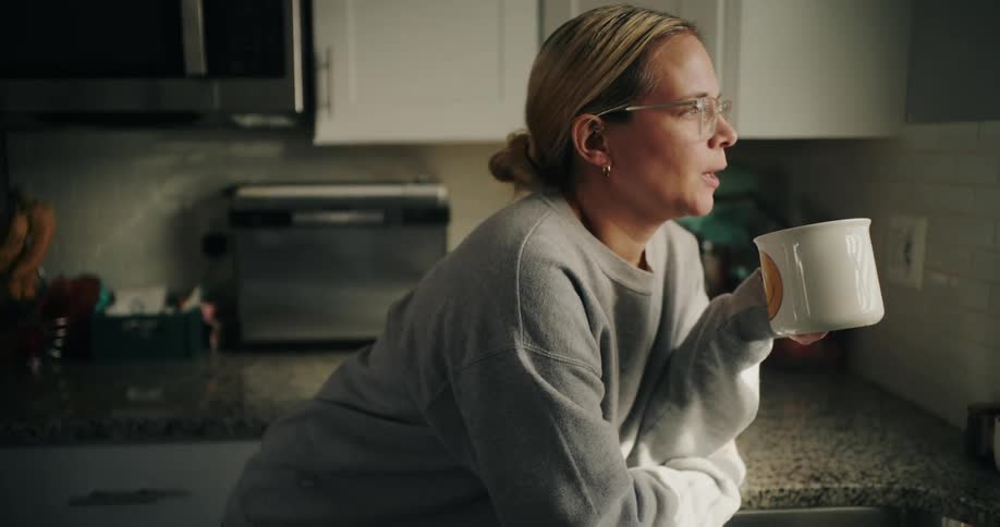 Woman in a kitchen drinking from a mug