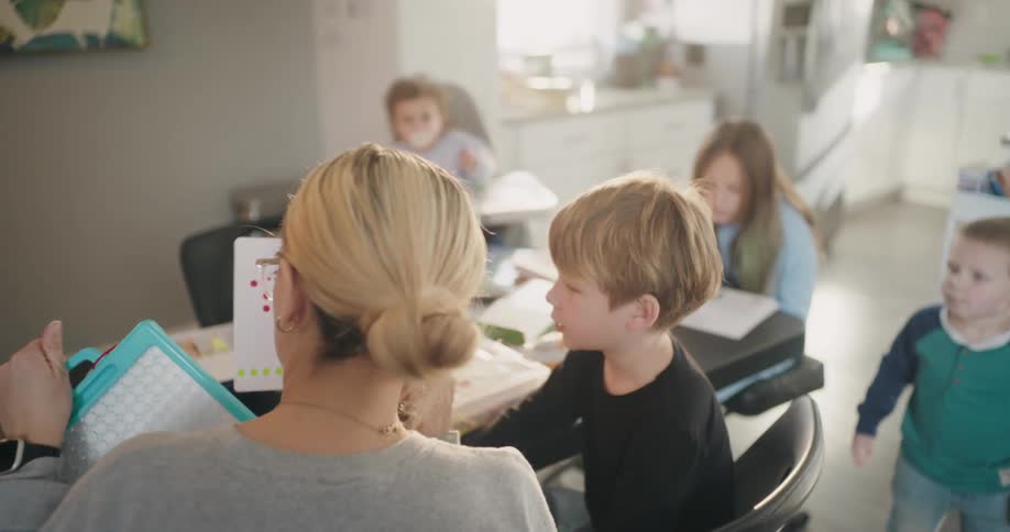 A mother teaching homeschool children in the kitchen