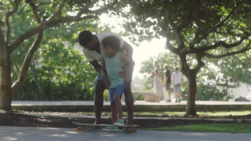 A father teaching his son to balance on a skateboard