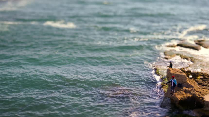 Two men are fishing on the rocks by the shore