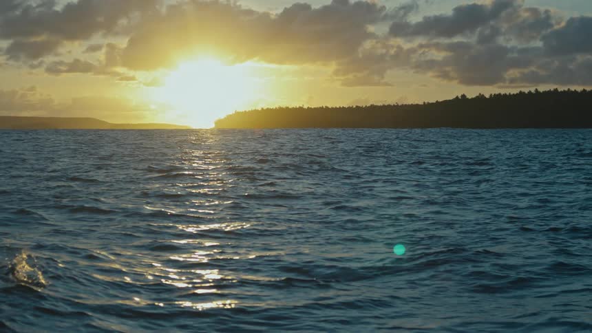 The sun is setting in the horizon of the ocean and landscape