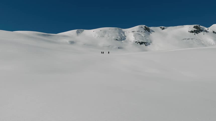 Landscape of a vast snowy mountain and three people walking on the horizon