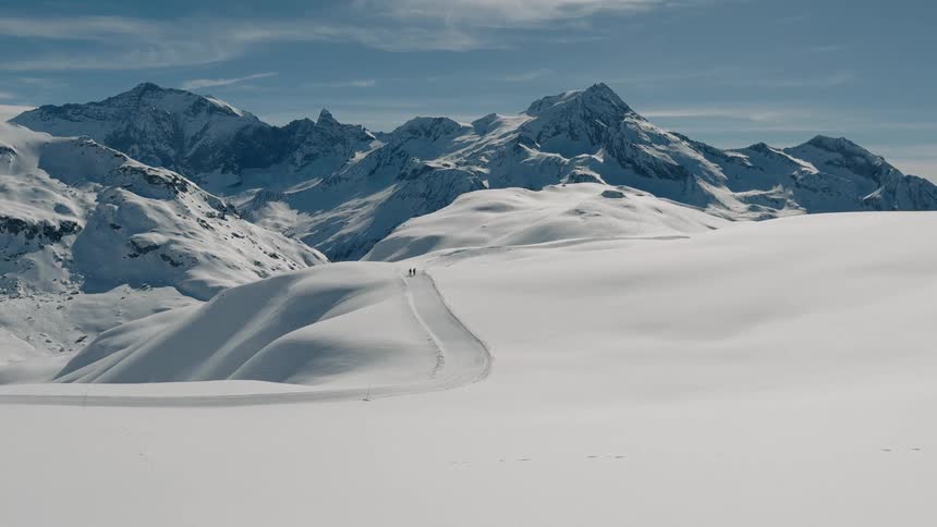 Two people are hiking in the distance across the mountain range