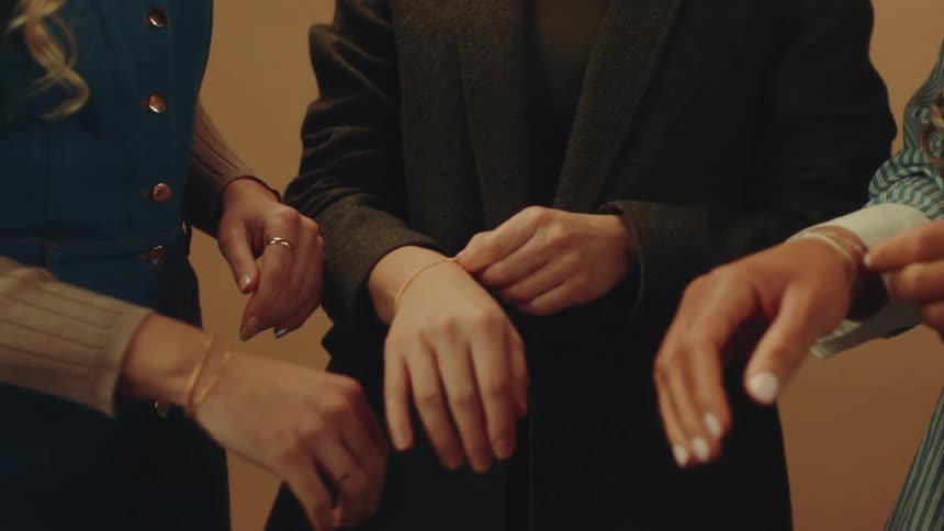 Arms of three women checking bracelets on their own wrists