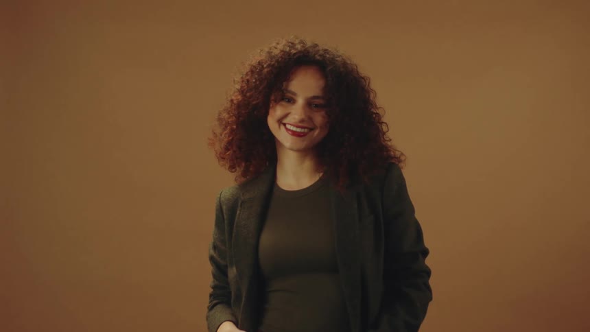 A woman is wearing a light jacket and smiling with joy