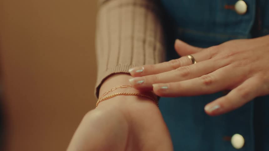 Woman checking gold bracelets on her own wrist