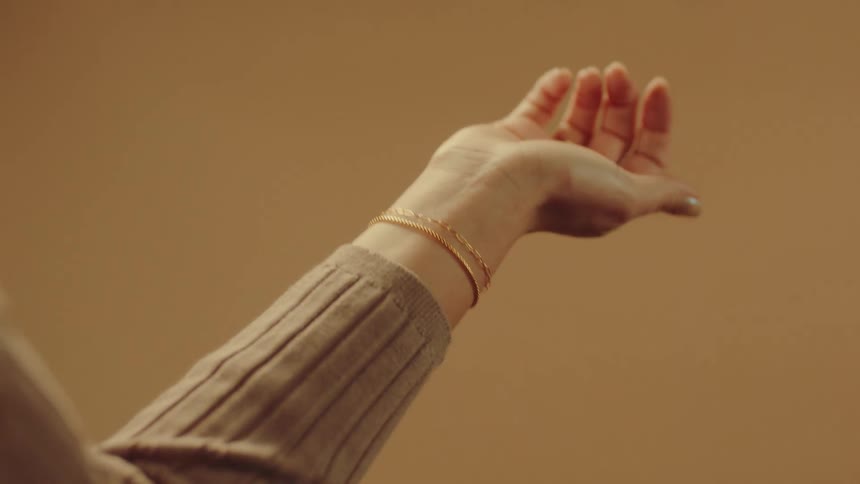 A woman is admiring a gold bracelet on her wrist
