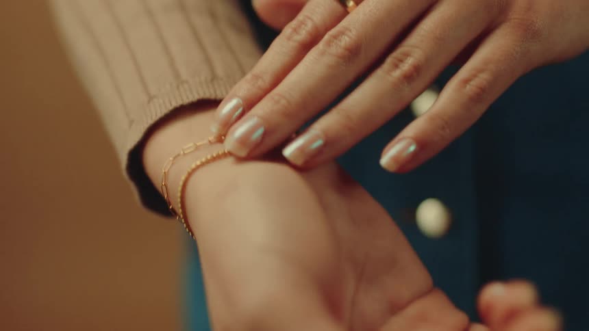 Woman is adjusting gold colored bracelets on her wrist